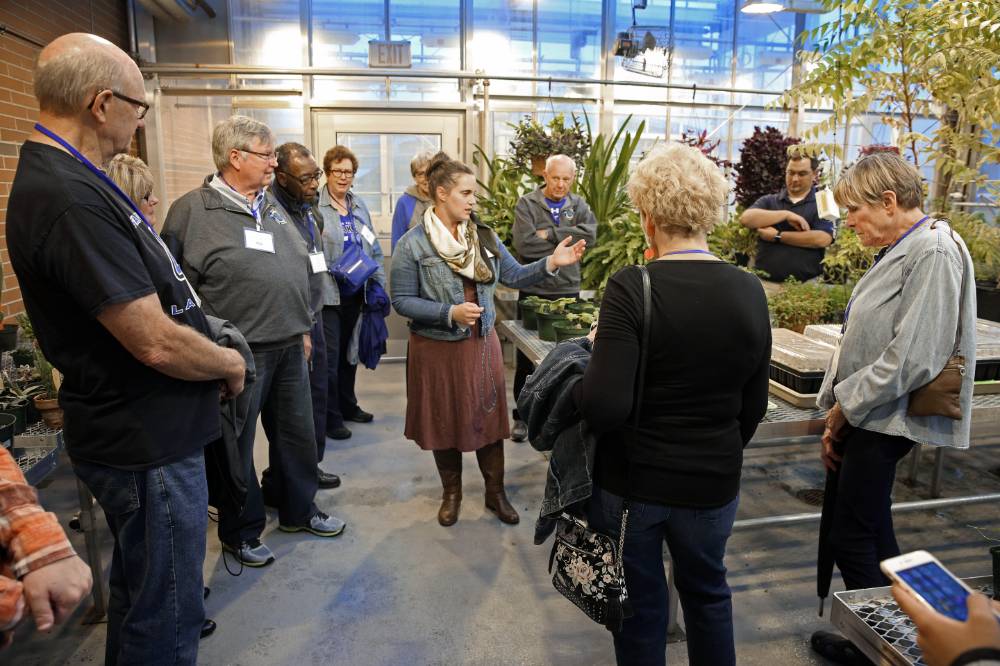 Class of '68 listens to the tour guide as she guides them through the greenhouse at Kindschi Hall.